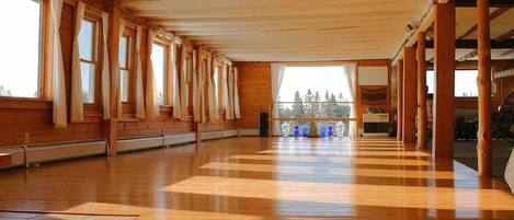 A spacious room with wooden floors, large windows, and a view of trees.
