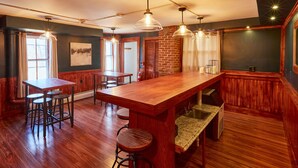 A kitchen with a wooden bar, stools, pendant lights, and a brick wall. - Home Near Hiking Biking w Hottub 6 Bedrooms (Bennington)