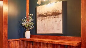 A corner of a room with wooden paneling, two stools, a potted plant, and a framed picture on the wall. - Home Near Hiking Biking w Hottub 6 Bedrooms (Bennington)