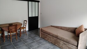 A minimalist room with a sofa, a dining table with chairs, and a black pendant light. - ART on the ground floor and terrace  (Beautheil-Saints)