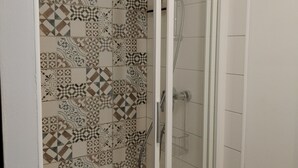 A shower with a geometric tile pattern on the wall and a clear glass door. - ART on the ground floor and terrace  (Beautheil-Saints)