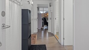 Ein moderner Flur mit einem schwarzen Kühlschrank, einem Korbwäscher und einem schwarzen Teppich.