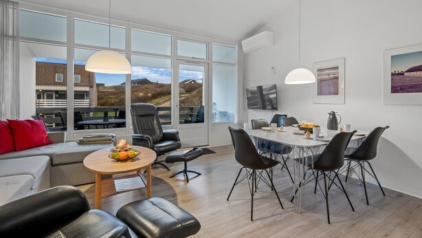 Ein modernes Wohnzimmer mit Essbereich, großen Fenstern und Blick ins Freie.