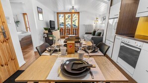 A modern kitchen with a dining area, wooden flooring, and a view of the outdoors. - Beautiful central apartment in Leukerbad (Leukerbad)