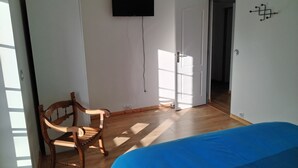 A room with a bed, a chair, a TV mounted on the wall, and a door leading to another room. - L' ART Appart from 2 to 4 pers, 7 min from coulommiers, 25 min from Disneyland Paris (Beautheil-Saints)
