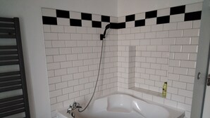 A bathroom with a freestanding bathtub, white tiled walls, and a checkered black and white tile border at the top. - L' ART Appart from 2 to 4 pers, 7 min from coulommiers, 25 min from Disneyland Paris (Beautheil-Saints)