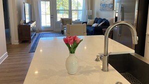 A modern kitchen with a central island, stainless steel appliances, and a view to the outdoors. - Spacious, New 4-bdrm townhome in charming Lewes, walk or bike to town & beaches! (Lewes)