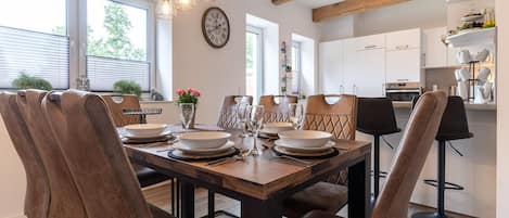 A dining area with a wooden table, leather chairs, and pendant lighting.