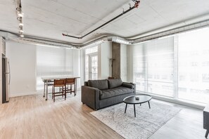 A spacious living room with a grey sofa, a round coffee table, and a dining area with a table and chairs. - 2BR/3BA combined apartments with  city views (Cleveland)