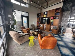 Uma sala de estar moderna com um sofá, poltronas, uma mesa de centro e uma televisão.