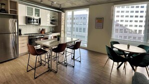 Een moderne keuken met roestvrijstalen apparatuur, een granieten aanrechtblad en een eethoek met een ronde tafel en stoelen.