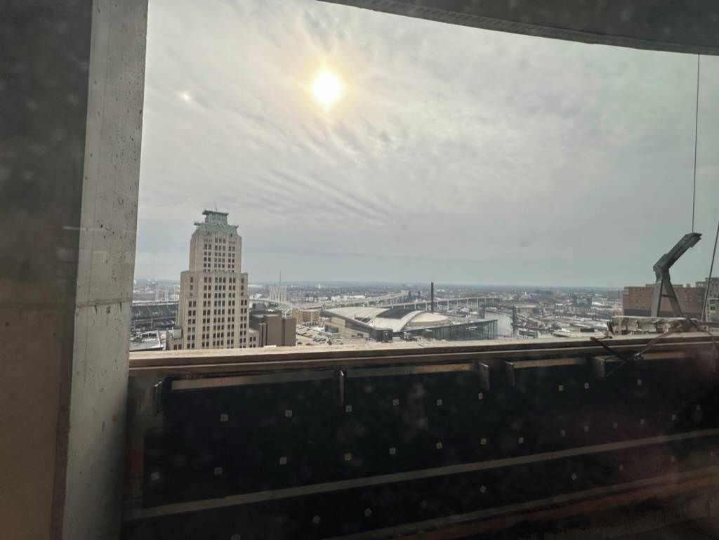 A view from a window overlooking a cityscape with a prominent building and a stadium.