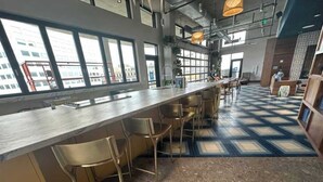 Een bar met een lange toonbank, meerdere krukken en een vloer met een patroon.
