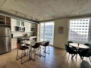 A modern kitchen with stainless steel appliances, a granite countertop, and a dining area with a round table and chairs.