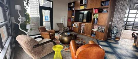 Un salon moderne comprenant un canapé, un fauteuil, une table basse et un téléviseur.