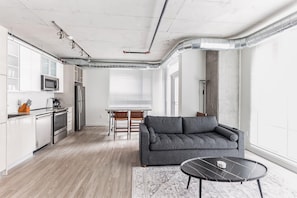 A modern kitchen with white cabinets, stainless steel appliances, and a dining area with a table and chairs. - 7 Combined units with Stunning City Views (Cleveland)