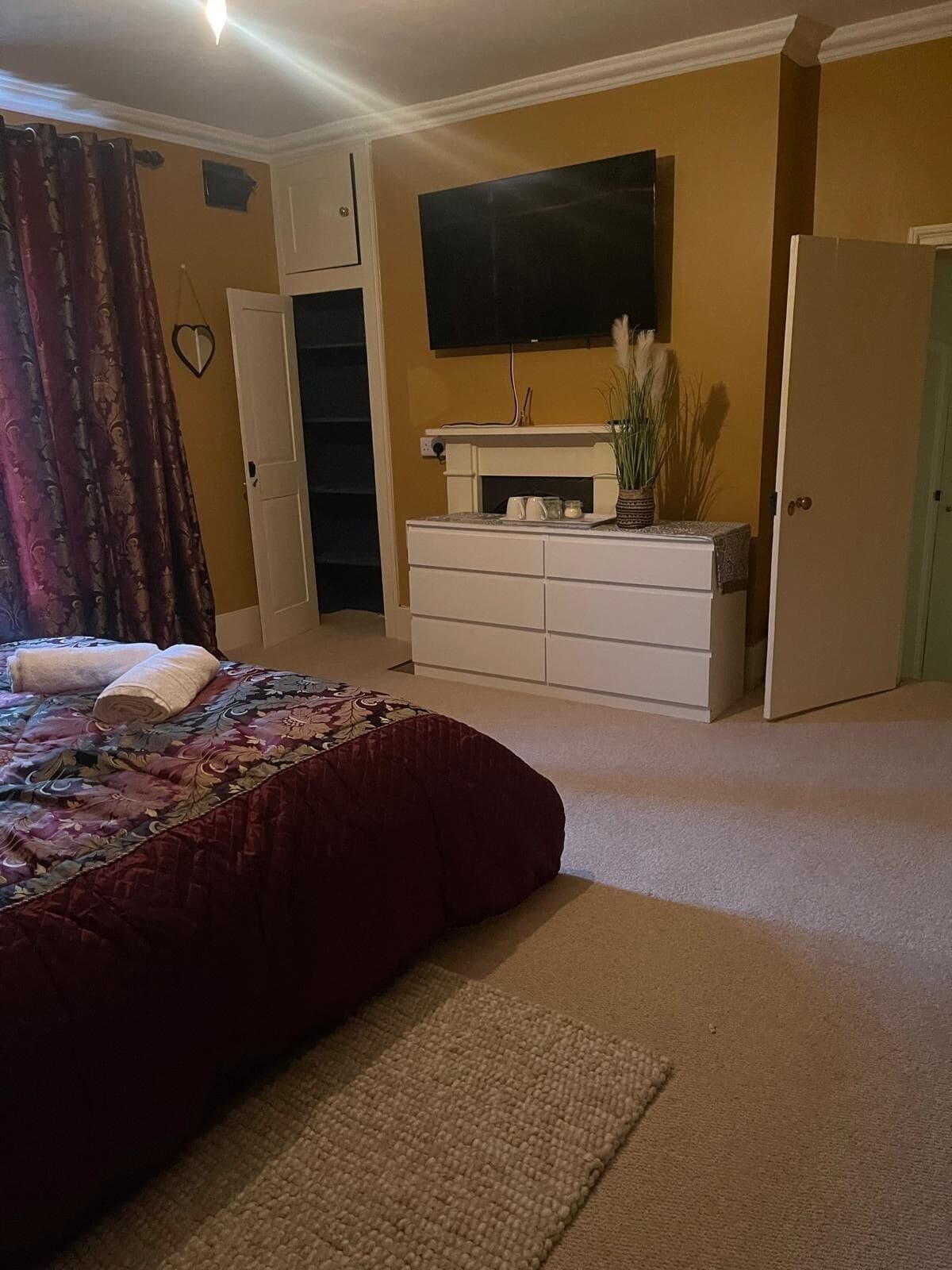 A bedroom with a bed, a dresser, a television, and a closet.