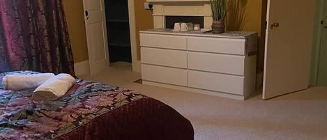 A bedroom with a bed, a dresser, a television, and a closet.