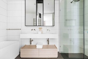 A modern bathroom with a white vanity, a mirror, and a glass shower enclosure.
