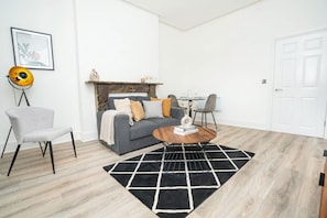 A living room with a sofa, armchair, coffee table, and a fireplace. - Charming 1-Bed Apt in Central Cheltenham (Cheltenham)
