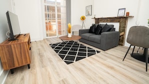 A modern living room with a grey sofa, a wooden coffee table, and a TV on a wooden stand.