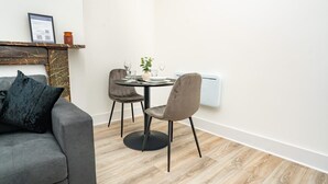 A modern living room with a grey sofa, a small dining table with chairs, and a fireplace.
