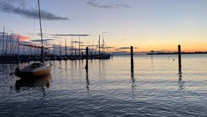 Un port de plaisance avec des bateaux amarrés à des quais en bois, une eau calme et un coucher de soleil en arrière-plan.
