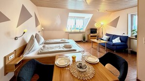 Une chambre moderne équipée d’un lit, d’une table à manger pour deux personnes, d’un canapé et d’un téléviseur.