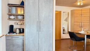 Une cuisine moderne avec des meubles de couleur grise, un plan de travail en bois et un coin repas comprenant une table et des chaises.