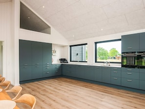 A modern kitchen with dark cabinets, a wooden dining table, and a large window.