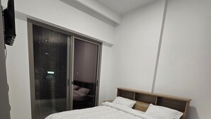 Un dormitorio con cama, armario y televisor.