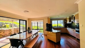 Una cocina moderna con armarios de madera, una isla central y una zona de comedor con una mesa larga y sillas.