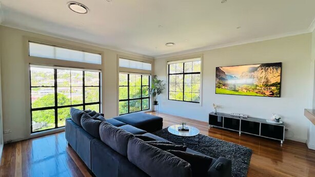 Un salón espacioso con un sofá modular grande, una mesa de centro y un televisor montado en la pared.