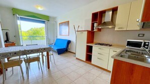 A compact kitchen with a dining area, a gas stove, a microwave, and a sink. - Apartment in Caorle Near Adriatic Sea (Caorle)