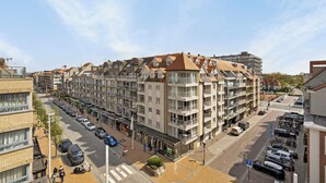 A multi-story residential building with balconies, a parking area, and a pedestrian walkway.
