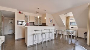 A modern kitchen with a central island, bar stools, and a dining area with a table and chairs.