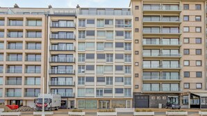 Un hôtel à plusieurs étages doté d’une architecture moderne, avec un patio central aménagé en espace de détente et une entrée couverte.