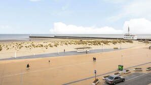 Une plage avec une promenade, une jetée et un bâtiment doté d’une tour.