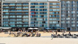 A multi-story hotel with balconies, outdoor seating, and a sandy beach area.