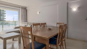 A modern dining area with a wooden table and chairs, a bench, and a view of the balcony. - 2 bedroom accommodation in Nieuwpoort (Nieuwpoort)