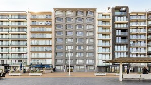Un hotel moderno de varios pisos con balcones, un patio central y zonas de estar al aire libre.