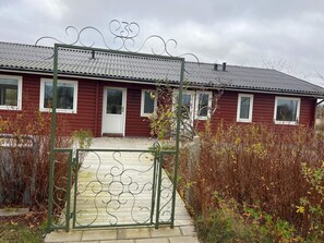 A red wooden house with a metal gate and a tiled roof. - 4 Star Holiday Home in Jerup (Jerup)