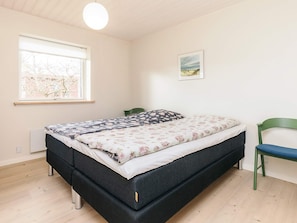 A bedroom with a bed, a chair, a window, and a wall-mounted light fixture. - 4 Star Holiday Home in Jerup (Jerup)