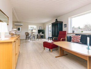 A spacious living area with a dining table, red armchair, and a large window providing a view. - 4 Star Holiday Home in Jerup (Jerup)