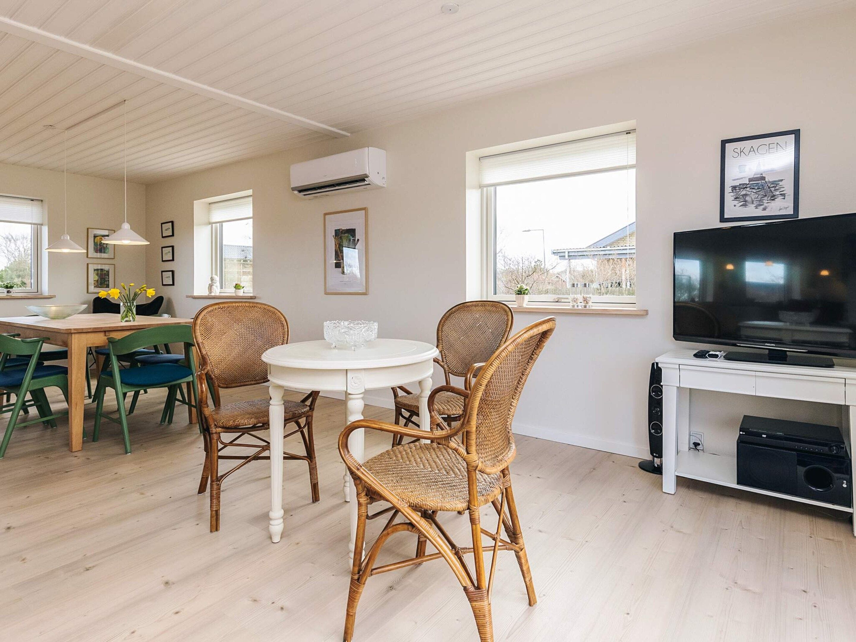 A modern living room with a dining area, a television, and a framed picture on the wall.