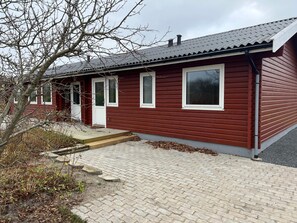 A red wooden building with a metal roof, a front door, and a small porch. - 4 Star Holiday Home in Jerup (Jerup)