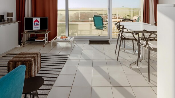 A modern living room with a TV, sofa, dining table, and chairs. - 1 bedroom accommodation in NIEUWPOORT (NIEUWPOORT)