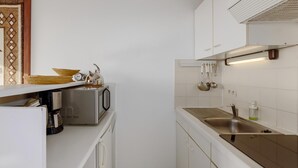 A compact kitchen with a microwave, coffee maker, and a sink with hanging utensils. - 1 bedroom accommodation in NIEUWPOORT (NIEUWPOORT)