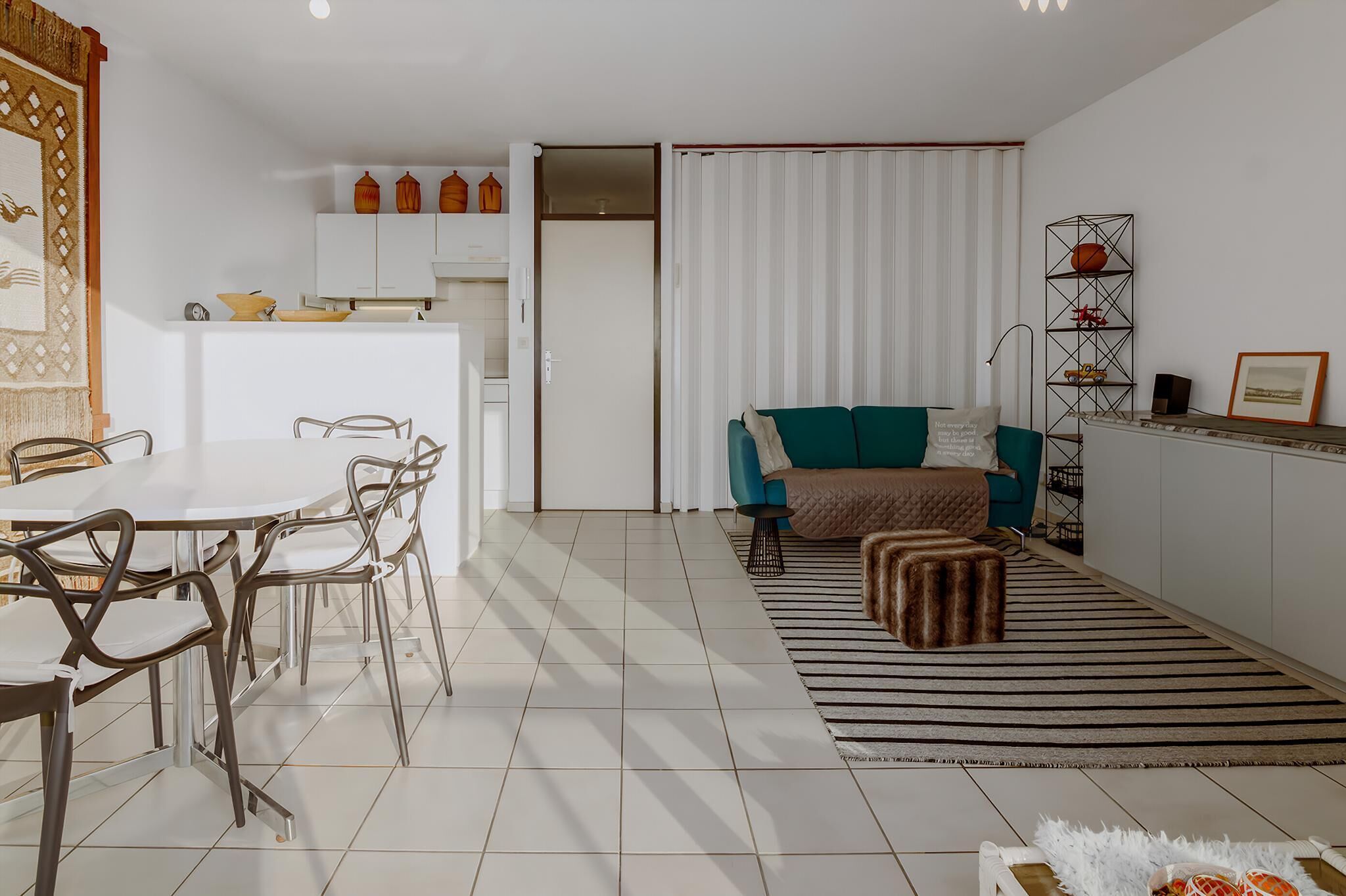 Un salon moderne comprenant un coin repas, un canapé, une table basse et un tapis à rayures.