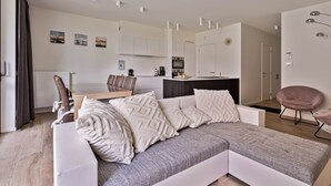 Un salon moderne avec un canapé, une table à manger et une cuisine en arrière-plan.
